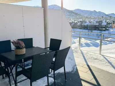 a black table and chairs on a balcony with snow at 4 star holiday home in HOVDEN in Hovden