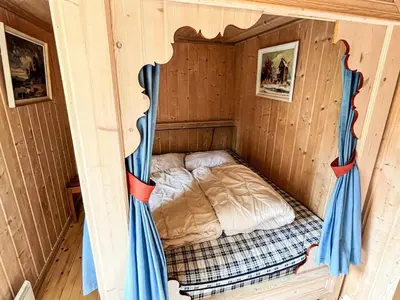 a bed in a wooden cabin with blue curtains at 4 star holiday home in gol in Gol