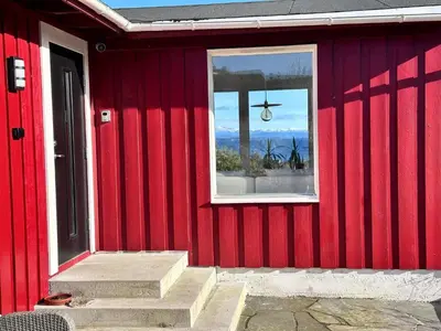 a red house with a window and stairs on it at 6 person holiday home in KLOKKARVIK in Klokkarvik
