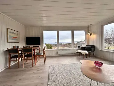 a living room with a table and chairs and windows at 6 person holiday home in KLOKKARVIK in Klokkarvik