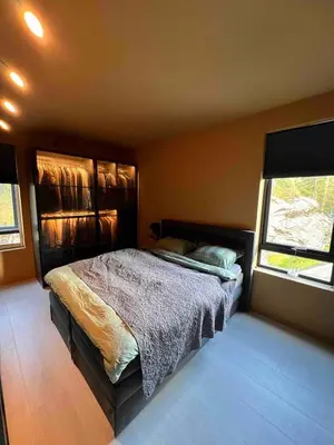 a bedroom with a bed and two windows at Luxury apartment with beautiful location in Florvåg