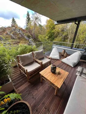 a wooden deck with two chairs and a table at Luxury apartment with beautiful location in Florvåg