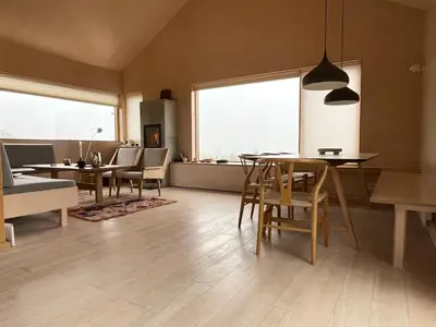 a living room with a table and chairs and windows at Birkenstua in Ringsaker