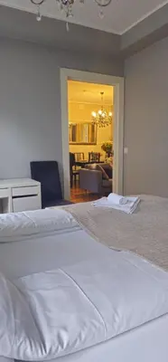 a bedroom with a white bed and a living room at Øvregaten in Bergen