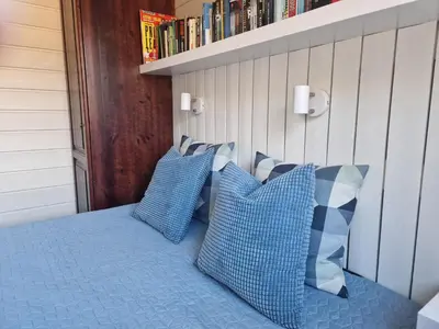 a bed with blue pillows and a book shelf at Storehorn Apartments Hemsedal in Fausko