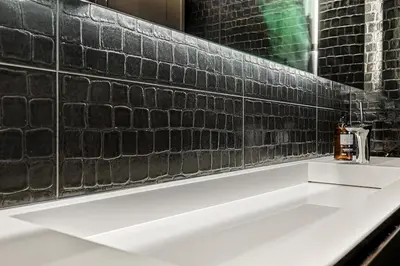a bathroom with a white sink and a brick wall at Exclusive Penthouse with Bryggen Views I MUST SEE in Bergen