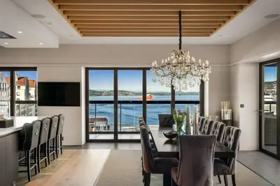 a dining room with a table and chairs and a chandelier at Exclusive Penthouse with Bryggen Views I MUST SEE in Bergen