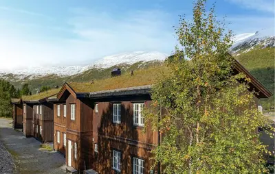 a building with a grass roof with mountains in the background at 2 Bedroom Cozy Apartment In Stranda in Stranda