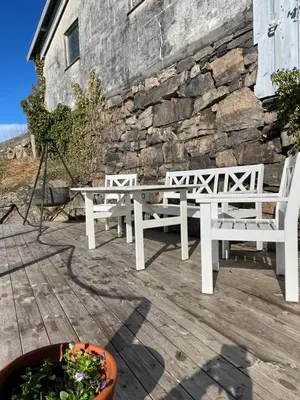 two white benches sitting on a deck next to a stone wall at Sjøutsikt in Bergen