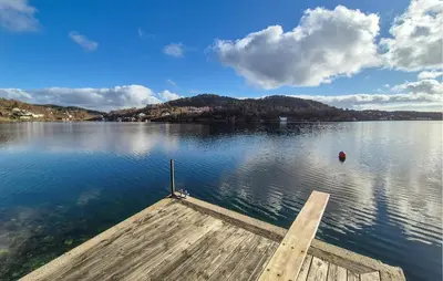 a wooden dock on a large lake with a view at Lovely Home In Mosterhamn With Sauna in Mosterhamn
