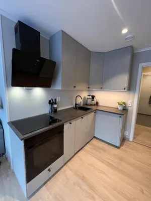 a kitchen with white cabinets and a black counter top at Mountain View apartment in Isfjorden