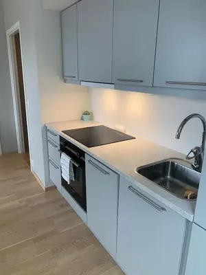 a kitchen with white cabinets and a sink at Bølgen Nyhavna in Trondheim