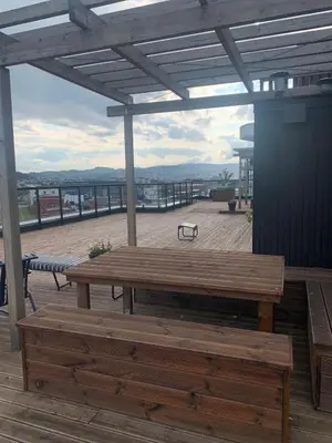 a wooden table and bench on a deck with a view at Bølgen Nyhavna in Trondheim