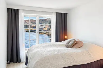 a bedroom with a bed with a large window at Komfortable Ferieleiligheter med Sjøutsikt in Stadlandet