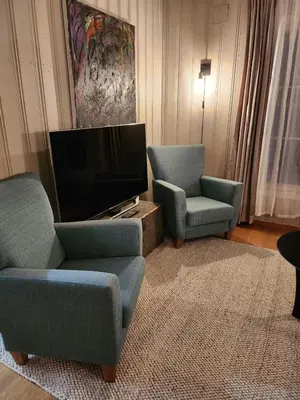 a living room with two chairs and a flat screen tv at Idyllic Snekkerstuvarpet with its own pier in Lillehammer