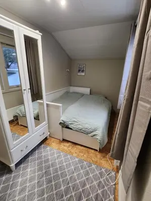 a small bedroom with a bed and a mirror at Idyllic Snekkerstuvarpet with its own pier in Lillehammer