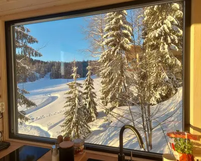 a kitchen window with a view of a snow covered field at LAUV Tretopphytter in Eidsvoll