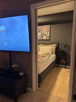 a bedroom with a bed and a flat screen tv at 3-room downtown apartment in Trondheim