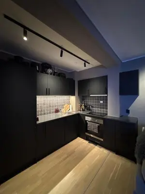 a kitchen with black cabinets and a wooden floor at 3-room downtown apartment in Trondheim
