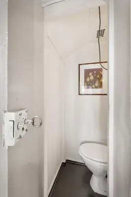 a white bathroom with a toilet and a picture at Bergen Gem Straight Out of History - Built in 1750 in Bergen