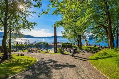 a crowd of people walking around a park near the water at Nice appartment in Bergens best location in Bergen