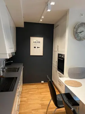 a kitchen with a clock on a black wall at Centrally located apartment in Bergen