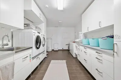 a kitchen with white cabinets and a washer and dryer at Villa Vy - a gem with private beach in Bergen in Bergen