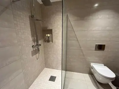a bathroom with a toilet and a glass shower at Villa Vy - a gem with private beach in Bergen in Bergen