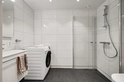 a white bathroom with a shower and a washing machine at Helt ny leilighet Ytre Sandviken in Bergen