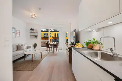 a kitchen with a sink and a living room at Helt ny leilighet Ytre Sandviken in Bergen