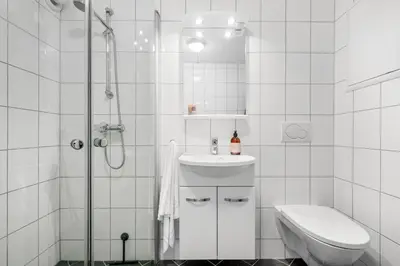 a white bathroom with a shower and a sink and a toilet at Bergen Beds - Modern, Cozy & Perfect Location in Bergen
