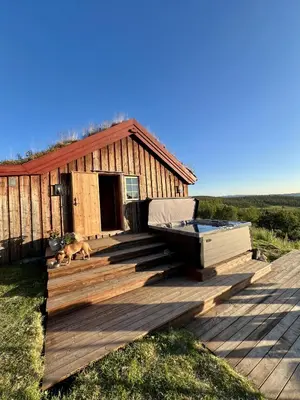 a deck with a hot tub and a dog in front of a house at The Heritage Lodge - Geilo in Geilo