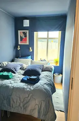 a bedroom with a bed with blue walls and a window at Home is where your heart is! in Bergen