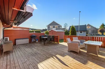 a wooden deck with chairs and a table on it at Hus i Verdal med 3 soverom in Verdal