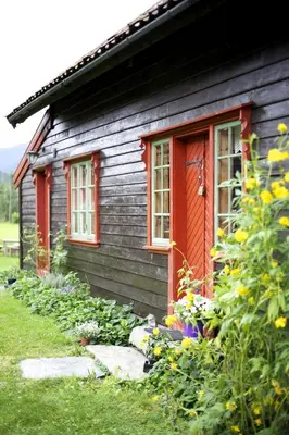 a house with red doors and flowers in front of it at Mo Laksegard in Sand
