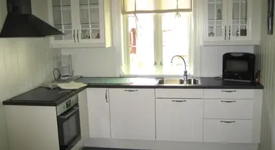a kitchen with white cabinets and a sink and a microwave at Jordbærstova Feriehus in Valldal