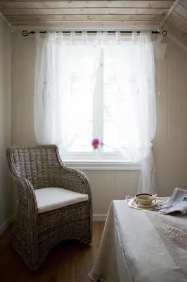 a bedroom with a wicker chair and a window at Jordbærstova Feriehus in Valldal