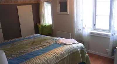 a bedroom with a bed and two windows at Jordbærstova Feriehus in Valldal