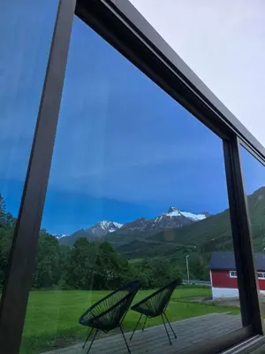 two chairs sitting in front of a window with mountains at Hytte Grøtdalstind, Rekkedal Gjestegard - Sæbø in Sæbø