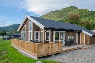 a house with a large deck with a mountain in the background at Pluscamp Mageli in Bjørge