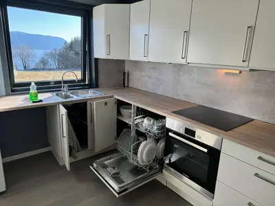 a kitchen with an open dishwasher next to a sink at New apartment by the fjord in Stadlandet