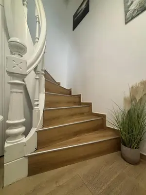 a stairway with a white rail and wooden stairs at Comfortable apartment in Ålesund in Ålesund