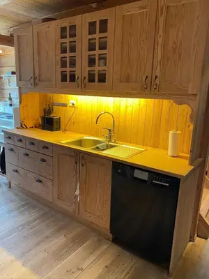 a kitchen with wooden cabinets and a sink at Stort hus med tømmervegger og fjordutsikt in Stranda
