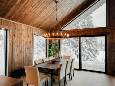 a dining room with a table and chairs and windows at Modern Cabin With Mountain View By Syningtoppen in Torpo