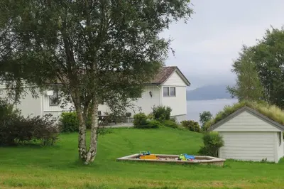 a boat in a yard next to a house at Sara's Fjord View House in Stadlandet
