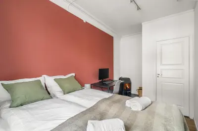 a bedroom with a bed and a red wall at Colorful Apartment - Right Next to Grieghallen! in Bergen