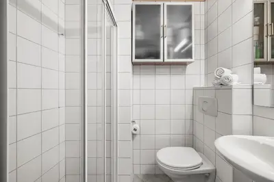 a white bathroom with a toilet and a sink at Colorful Apartment - Right Next to Grieghallen! in Bergen
