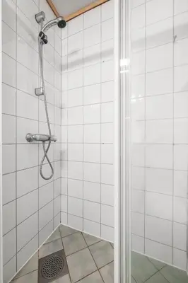 a shower in a white tiled bathroom at Colorful Apartment - Right Next to Grieghallen! in Bergen