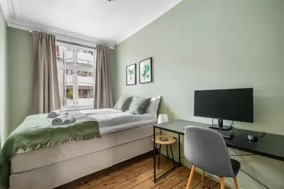 a bedroom with a bed and a desk with a computer at Colorful Apartment - Right Next to Grieghallen! in Bergen
