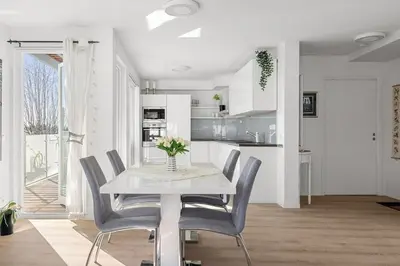 a white dining room with a table and chairs at A cozy three bedroom apartment for rent in Heimdal